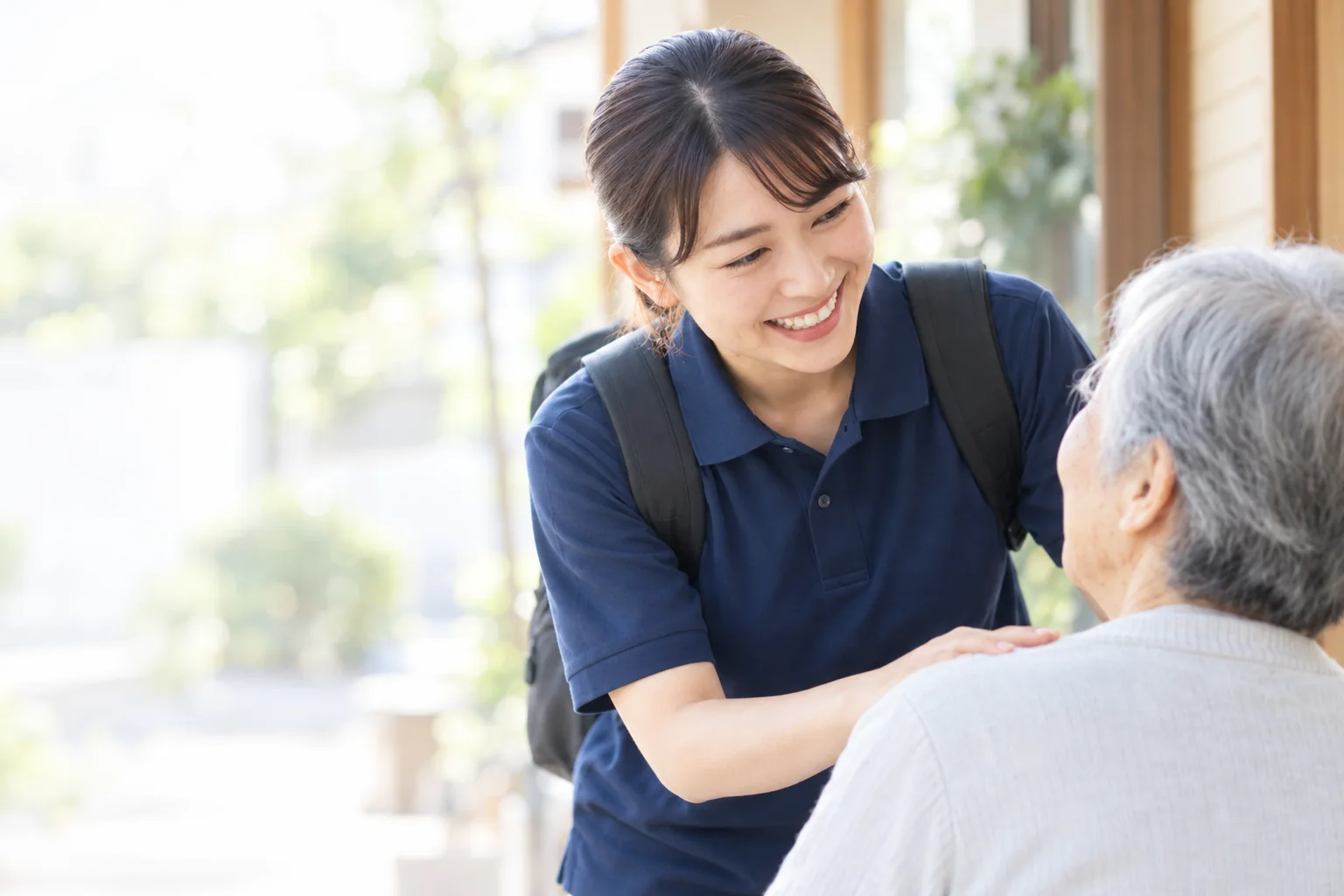 利用者さんの肩にそっと手を添え、笑顔で話しかけるヘルパー